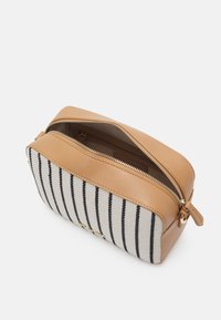 Kosmetická taška se zipem v horní části s hnědou syntetickou kůží a béžovou látkou, na které jsou černé vertikální pruhy. Akcenty zlatého zipu a kovových komponentů.