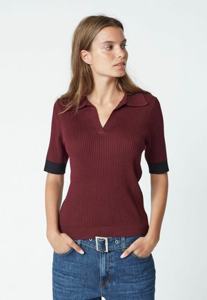 Burgundy ribbed pullover with a V-neck and short black cuffed sleeves, made of a soft, stretchy material. Classic fit with subtle texture.