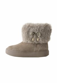 Faux fur gevoerde, taupe enkelboot met een zachter suede buitenlaag, ronde neus en decoratieve strikjes met gouden accenten. Platte rubberen zool.