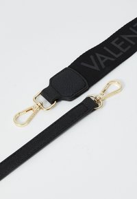 Bande en tissu noir et sangle en cuir avec un clip en or, présentant une finition texturée et le lettrage en relief "VALENTINO" sur la bande supérieure.