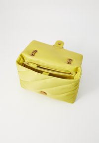 Μαλακή κίτρινη τσάντα χειρός από λείο υλικό, με κλειστό άνοιγμα τύπου φλάντζας, χρυσές λεπτομέρειες και εσωτερική τσέπη με φερμουάρ.