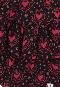 Zwarte stof met een patroon van roze harten en sterburst. Heeft een gerimpeld gelaagd ontwerp en een gladde textuur.