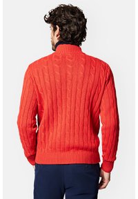Czerwony sweter z dzianiny warkoczowej z wysokim kołnierzem, ściągaczami na rękawach i u dołu. Posiada teksturowany wzór oraz kontrastujący ciemny kołnierz.