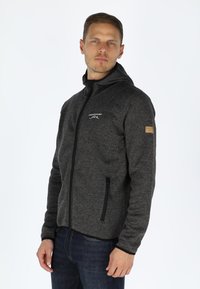 Grijze fleece hoodie met rits, hoge kraag, zijzakken en een logo op de borst. De stof heeft een gestructureerde uitstraling.