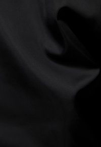 Svart tyg med en slät textur, hopfällt i veck, som visar en rik, djup färg och subtil lyster. Inga mönster eller beslag synliga.