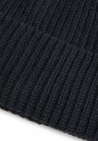 Czarna dzianina o żebrowanej fakturze, z głębokimi rowkami i garbami, zapewniająca miękki i ciepły wygląd.