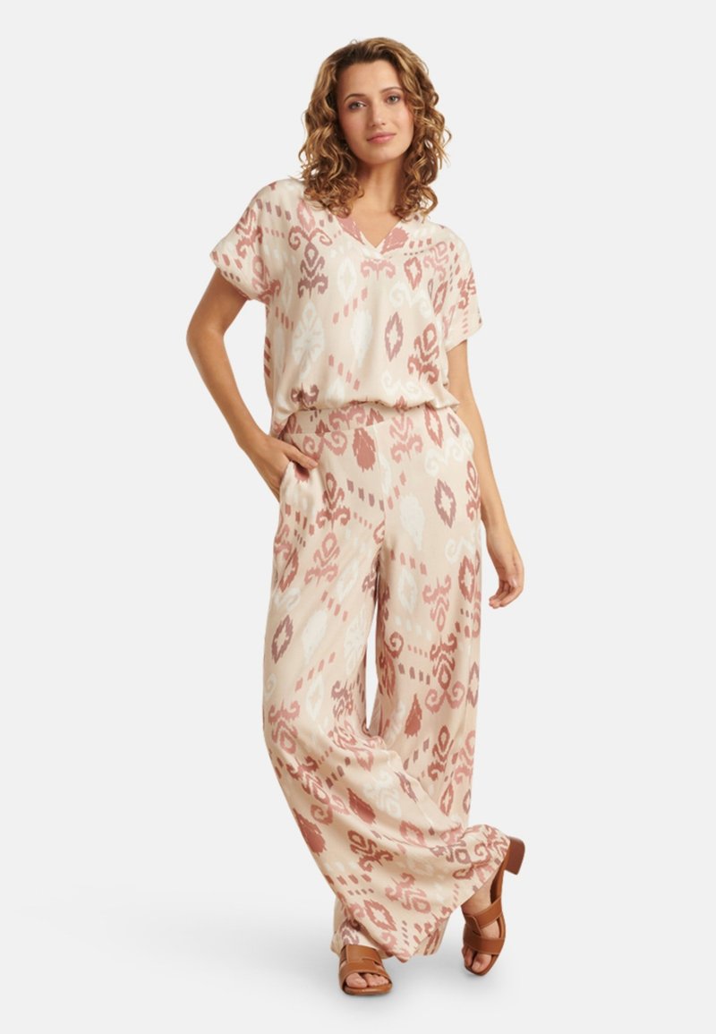 Lightweight, pale pink two-piece set with a V-neck top and wide-leg pants. Features a subtle geometric pattern in darker pink and beige.