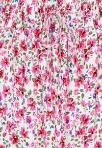 Tessuto floreale con fiori rosa e rossi su sfondo bianco, accompagnati da foglie verdi. Vita elastica con dettaglio di fiocco legato.