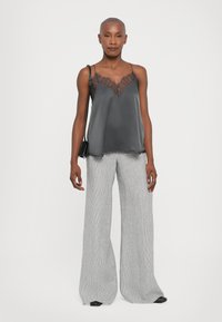 Gray satin camisole with sheer lace detailing at the neckline, paired with wide-legged striped trousers in light gray. Black shoulder bag included.