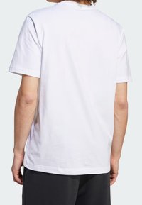 T-shirt in cotone bianco con collo rotondo classico e maniche corte, caratterizzato da una texture liscia e una vestibilità rilassata, visto da dietro.