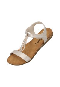 Sandal de color beige claro con suela plana, que presenta una tira metálica en la punta y una tira en el tobillo. Textura de ante suave en la plantilla.