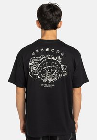 Zwarte katoenen t-shirt met een witte grafische afbeelding van een wezen op de achterkant, met de tekst "Kruip, Kroel of Rol" eronder.