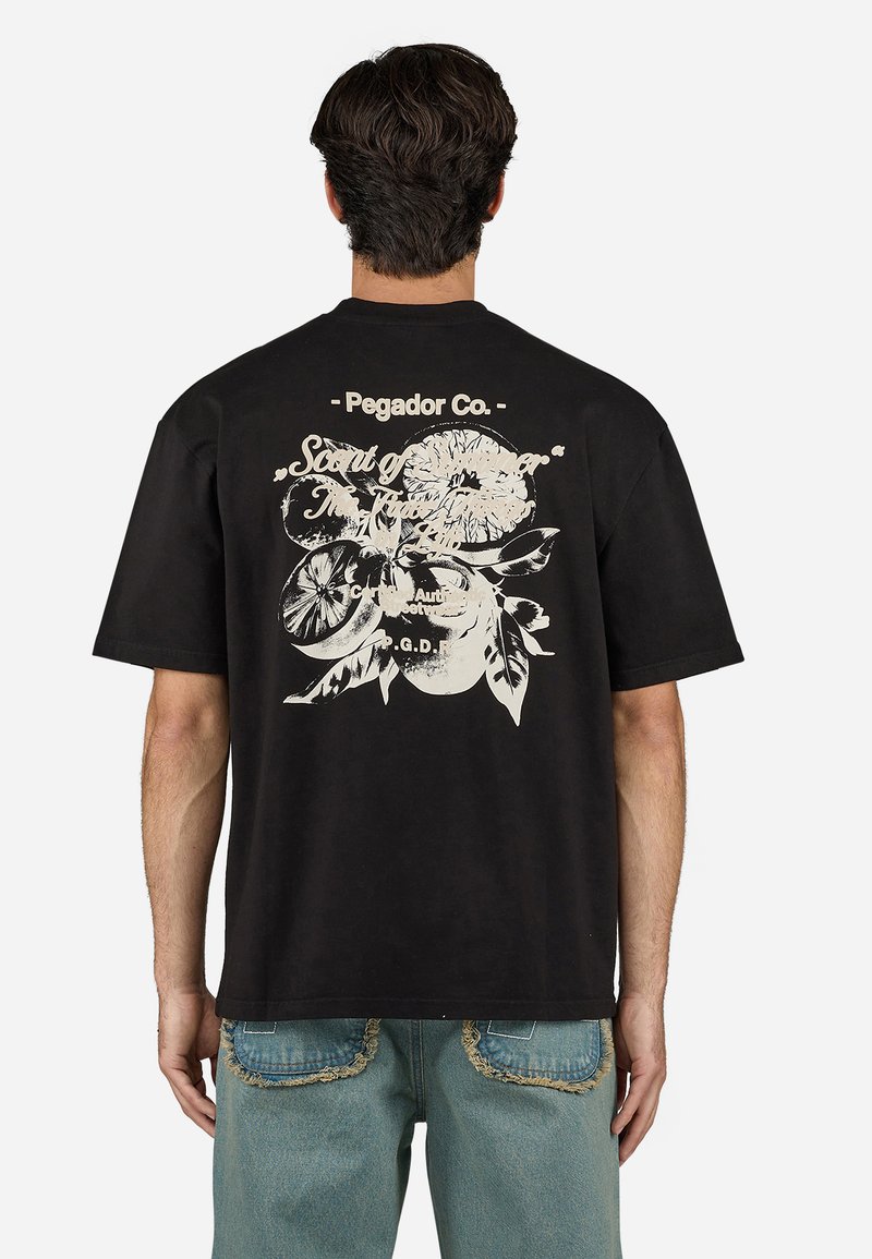 Sort bomulds t-shirt med et stort hvidt blomstermotiv og tekst på ryggen. Løs pasform og korteærmer. Rund halsudskæring.