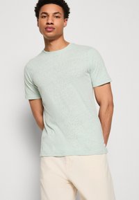 Μέντα πράσινο T-shirt κοντό μανίκι, κατασκευασμένο από ανάγλυφο ύφασμα, διαθέτει στρογγυλή λαιμόκοψη και μια μικρή λογότυπο λεπτομέρεια στο κάτω άκρο.