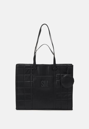 Sac cabas rectangulaire noir avec deux bretelles, côtés matelassés, monogramme "SM" embossé à l'avant, et petite pochette ronde attachée sur le côté droit.