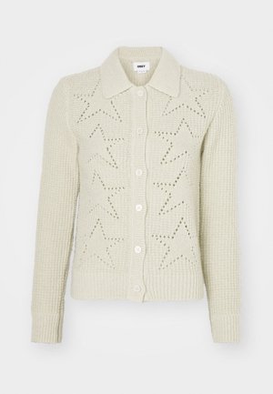 Bežový pletený kardigán s golierom, predným zapínaním na gombíky a vzorom s výrezmi v tvare hviezd. Hladké manžety a lem zdôrazňujú textúru.