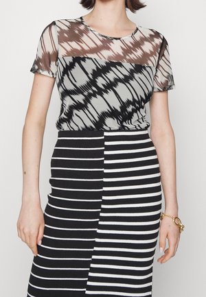 Doorzichtig, gebloemd topje met een bruin, zwart en grijs ontwerp. Hooggetailleerde zwart-wit gestreepte rok. Gladde textuur. Gouden armband zichtbaar.