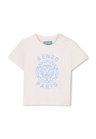 T-shirt rose clair à manches courtes en coton avec un graphique de lion bleu et le texte "KENZO PARIS" dans un design circulaire. Il possède des boutons-pression sur l'épaule.