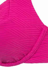 Rožinė bikini viršūnė su tekstūruota chevron raštu, paminkštinta forma ir tvarkingais siūlėmis kraštuose. Atrodo, kad medžiaga yra elastinga.