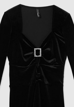 Abito in velluto nero con maniche lunghe, scollatura a V e corpino arricciato. Presenta una fibbia quadrata in strass in vita per un tocco di eleganza.