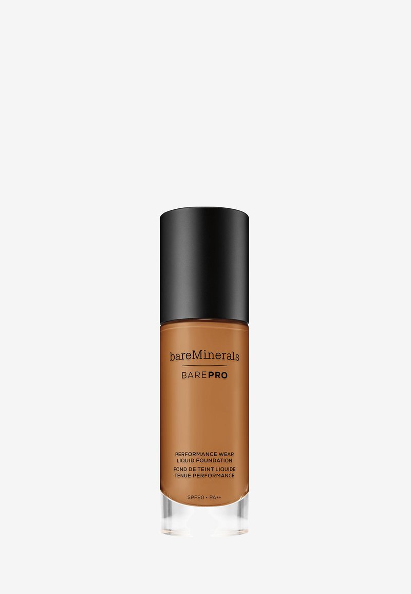 Base líquida BAREPRO de BareMinerals en un frasco marrón con un dosificador negro mate. La base clara revela el producto en su interior. SPF 20.