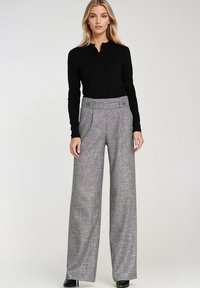Czarna bluzka z długimi rękawami i kołnierzykiem na guziki w połączeniu z szarymi szerokimi spodniami o fakturowanym splot oraz podwójnym zapięciem w pasie.
