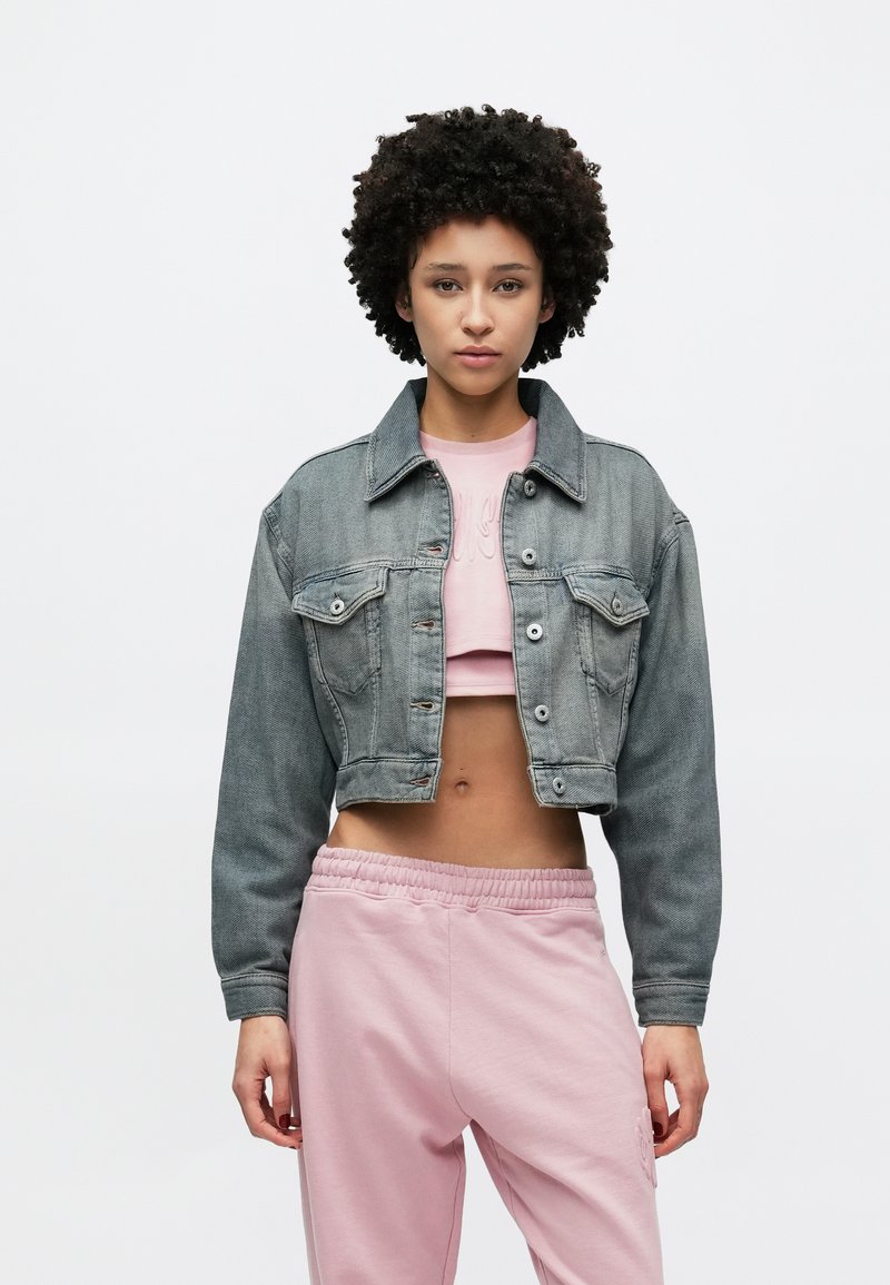 Γκρι cropped τζιν μπουφάν με κουμπιά, δύο μπροστινές τσέπες και μακριά μανίκια, συνδυασμένο με ροζ cropped τοπ και αντίστοιχο παντελόνι φόρμας.