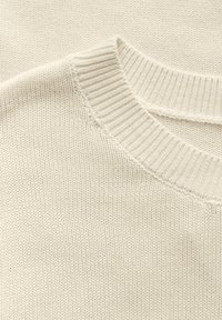 Pull en maille beige clair avec un col rond côtelé et un motif texturé. Présente une conception sans coutures aux épaules et un tissu doux.