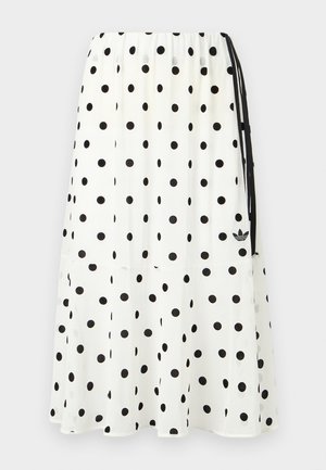 Jupe midi blanche à pois noirs, taille élastique, lien latéral et petit logo Adidas noir près de l'ourlet.