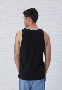 Zwarte katoenen tanktop met een ronde halslijn en brede armsgaten, met een eenvoudige uitstraling en een rechte zoom.