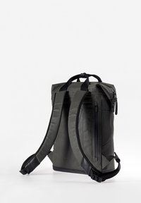 Zaino roll-top in materiale verde scuro. Presenta spallacci regolabili, tasca con zip laterale e tessuto resistente e idrorepellente.