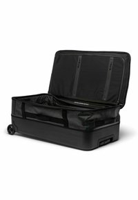 Sac de voyage à roulettes noir avec un fond rigide et une partie supérieure en tissu doux, muni de doublures à zippes, de poches internes et d'un compartiment ouvert spacieux.