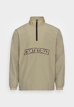 Veste-pullover beige avec demi-fermeture éclair et poignets élastiques arborant le logo "Santa Cruz" en grandes lettres créées en contour sur la poitrine.