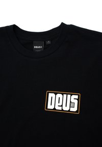 Black cotton t-shirt with a crew neck, featuring a white "DEUS" logo inside a rectangular orange outline on the chest.