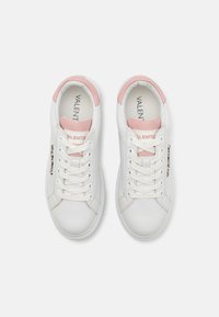 Hvite lær sneakers med rosa aksenter, med flate snørebånd, avrundet tå, og en logo detalj langs siden.