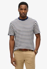 Gestreiftes Baumwoll-T-Shirt mit navyblauen und cremefarbenen horizontalen Streifen, geripptem Rundhalsausschnitt, kurzen Ärmeln und einem kleinen Logo auf dem linken Ärmel.