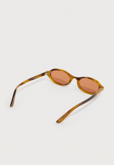 Καφέ οβάλ γυαλιά ηλίου με σχέδιο χελώνας και φακούς με κεχριμπαρένια απόχρωση, ανοιγμένα και τοποθετημένα πάνω σε λευκή επιφάνεια.