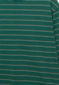 Cămașă verde din bumbac cu mâneci lungi, prezentând dungi orizontale în alb, albastru deschis și portocaliu. Textură moale cu design cu guler rotund.