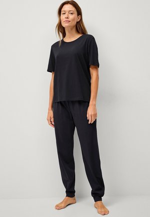 Zwarte katoenen T-shirt met korte mouwen en een ronde hals, gecombineerd met zwarte joggerbroek met elastische tailleband, beide met een ontspannen pasvorm.