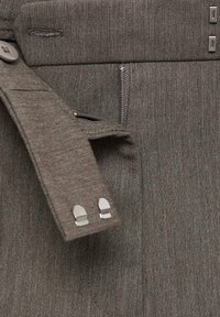Bruine getextureerde broeken met een knoopsluiting, een ritssluiting en metalen accenten op de tailleband. Netjes getailleerd ontwerp met strakke lijnen.