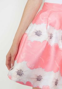 Falda floral con patrones en rosa y blanco, con un diseño plisado y una textura suave. La cintura es ajustada y sin costuras.
