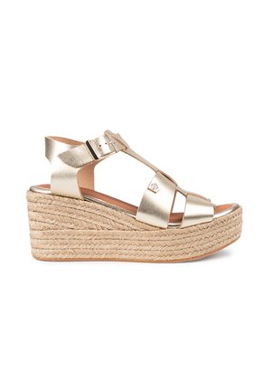 Sandalias de cuña metálicas doradas con plataforma de yute trenzado y correa al tobillo. Presentan un diseño de punta abierta y hebilla ajustable para un mejor ajuste.