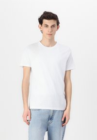Hvit bomulls t-skjorte med korte ermer, rund hals, brukt med lyseblå denimjeans med rett passform og minimalistisk design.