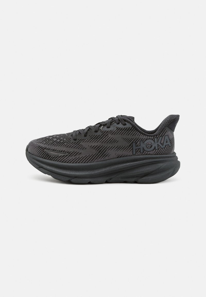Scarpe da ginnastica nere con tomaia in rete testurizzata, suola ammortizzata prominente e marchio HOKA sul lato. Mantiene un design elegante e moderno.