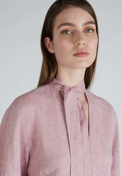 Blusa in lino rosa chiaro con design a nodo, caratterizzata da una sottile trama e un'apertura con pattina. Vestibilità morbida e rilassata con maniche lunghe.