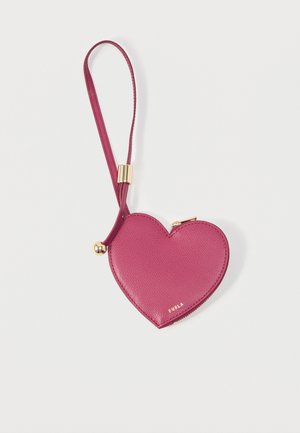 Monedero de cuero rosa en forma de corazón con cremallera dorada y correa para la muñeca, de la marca Furla, sobre un fondo blanco.