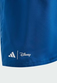 Blue athletic shirt made from smooth fabric, featuring white Adidas logo and Disney branding near the hem. Simple design with no patterns.