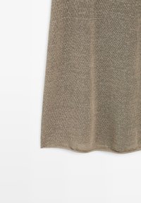 Tissu tricoté beige à texture fine, montrant la partie inférieure avec des plis drapés sur fond blanc.