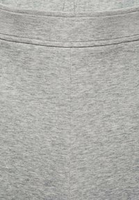 Tissu de pantalon de survêtement gris avec une texture subtile, présentant une taille plate et sans matériel ou motifs visibles. Surface lisse et sans embellissement.