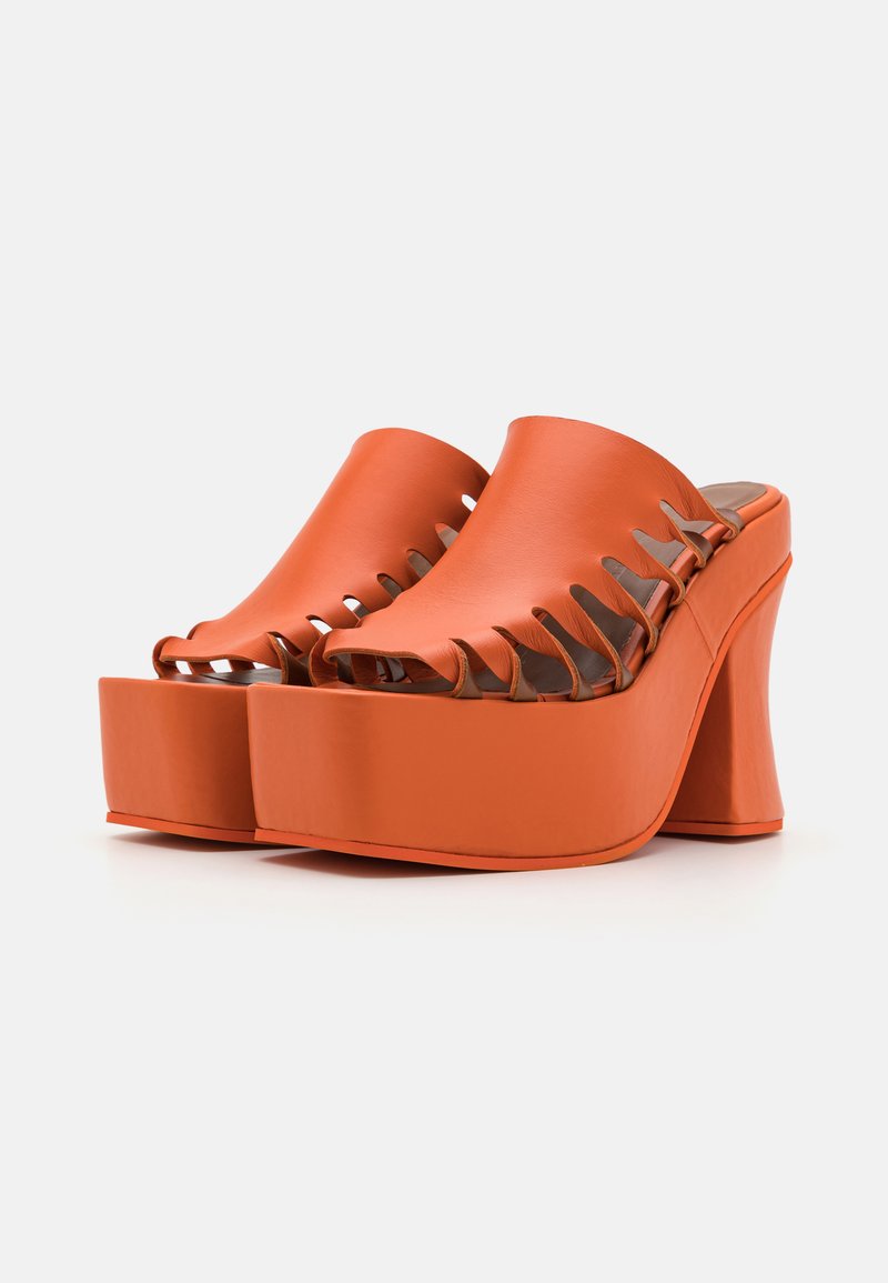 Oranje platform mules met een open teen, voorzien van een uitsnijdingen op de bovenkant. Gemaakt van een glad materiaal met een chunky hak.